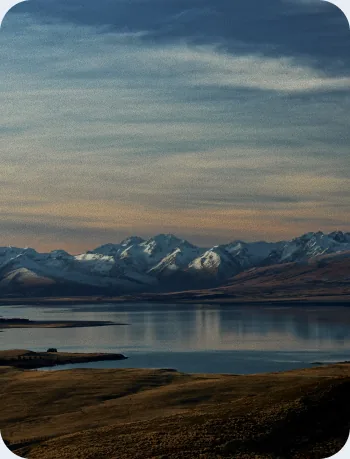 Snow-capped mountain range reflected in a calm lake at sunset