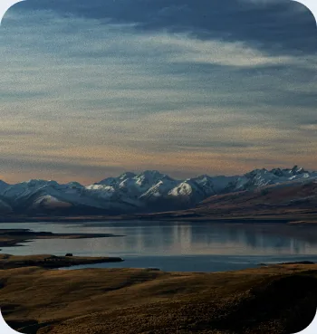 Snow-capped mountain range reflected in a calm lake at sunset