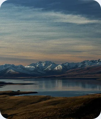 Snow-capped mountain range reflected in a calm lake at sunset