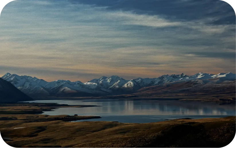 Snow-capped mountain range reflected in a calm lake at sunset
