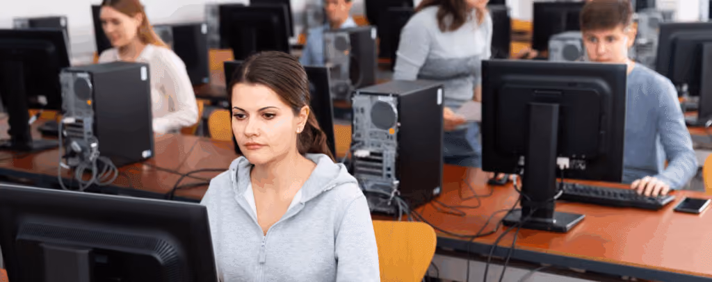 Alunos em uma sala com computadores realizando uma avaliação