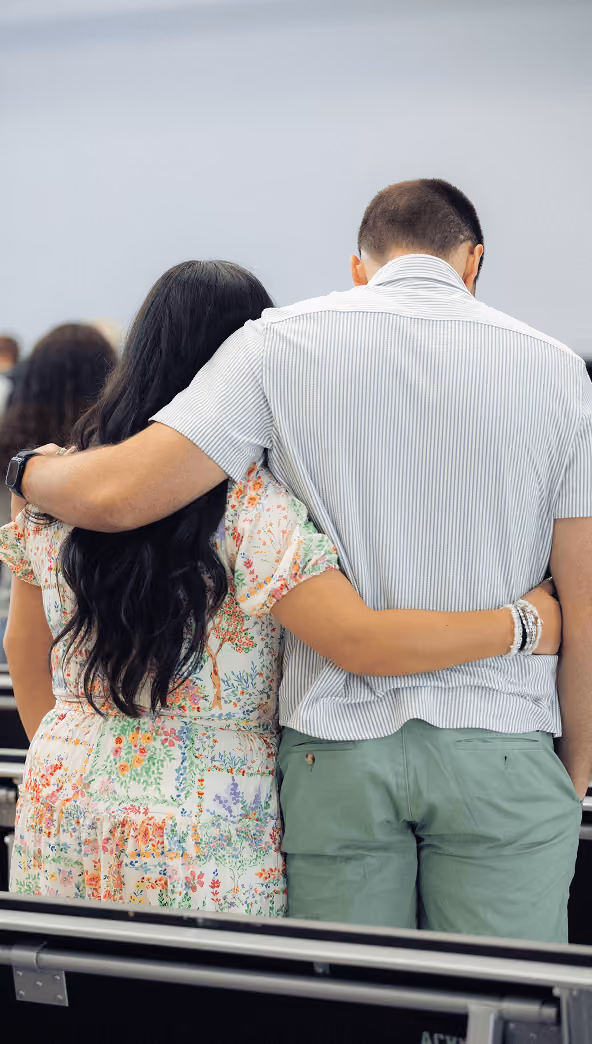 Couple embracing each other while sitting indoors with their backs to the camera.