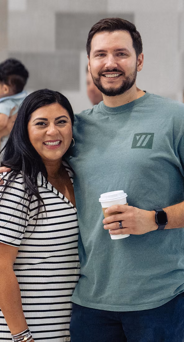 man and woman smiling at camera. holding coffee.