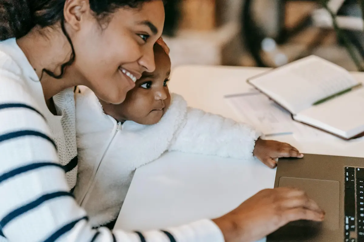 A young mom cuddles her child while working from home
