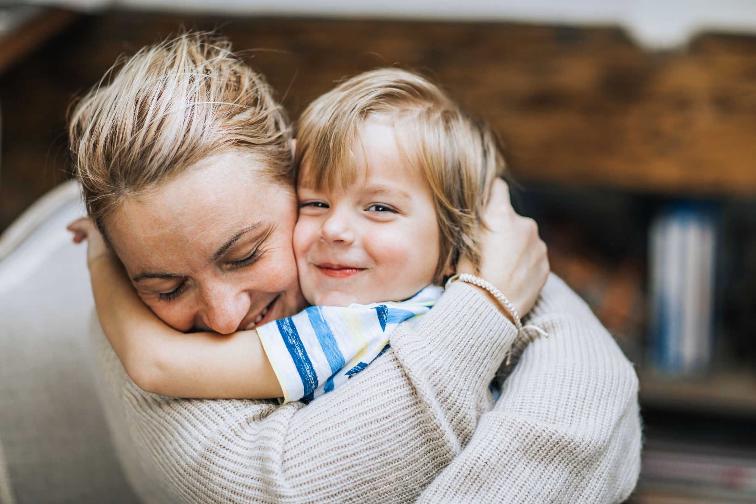 A mother hugs her smiling son