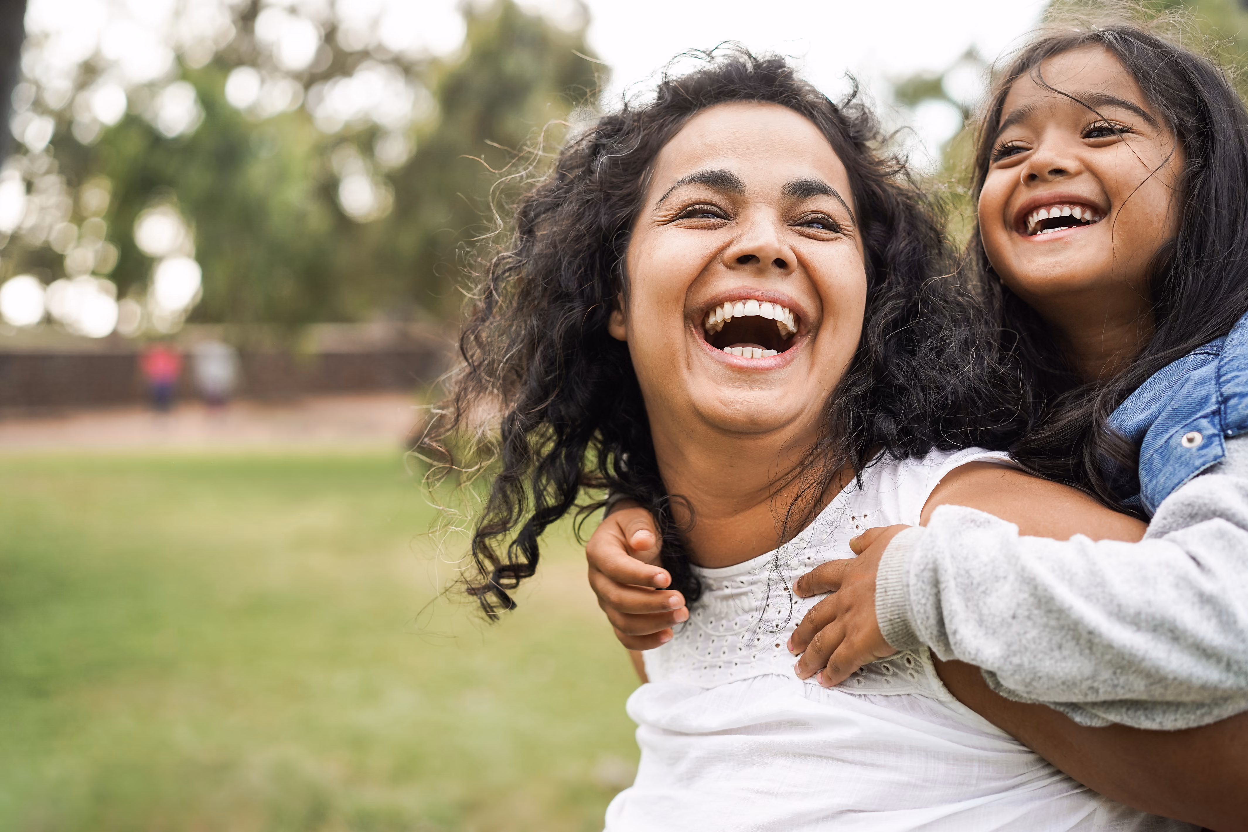 A mother laughs with her daughter on her back