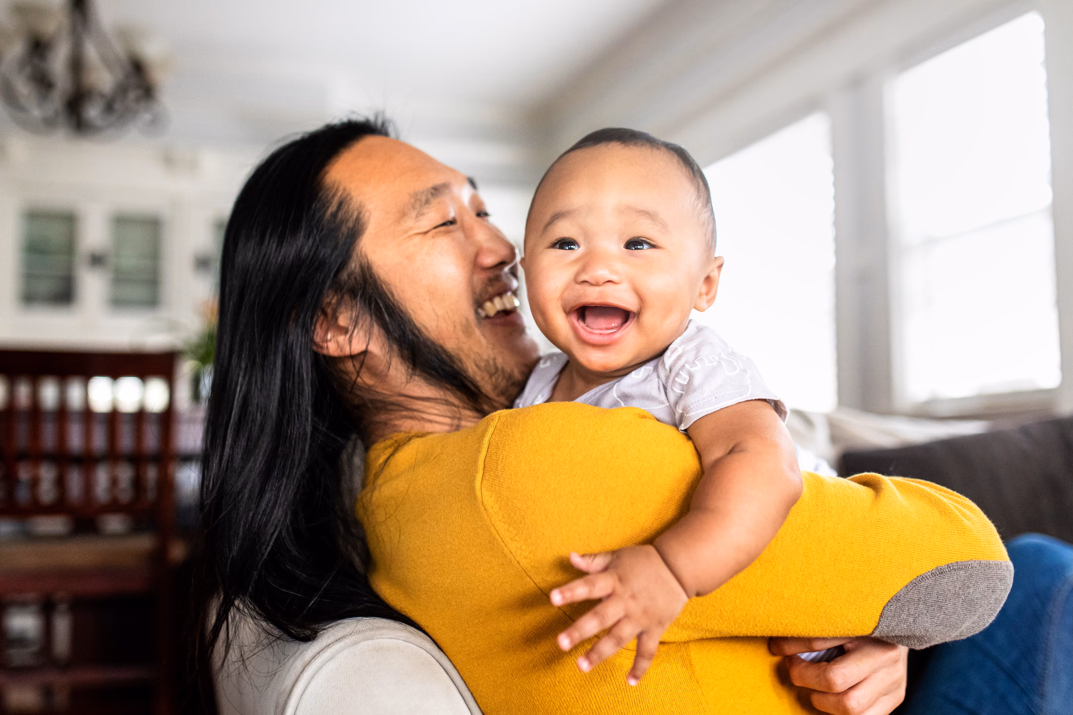 A father plays with his son in a cardboard box while the family cheers