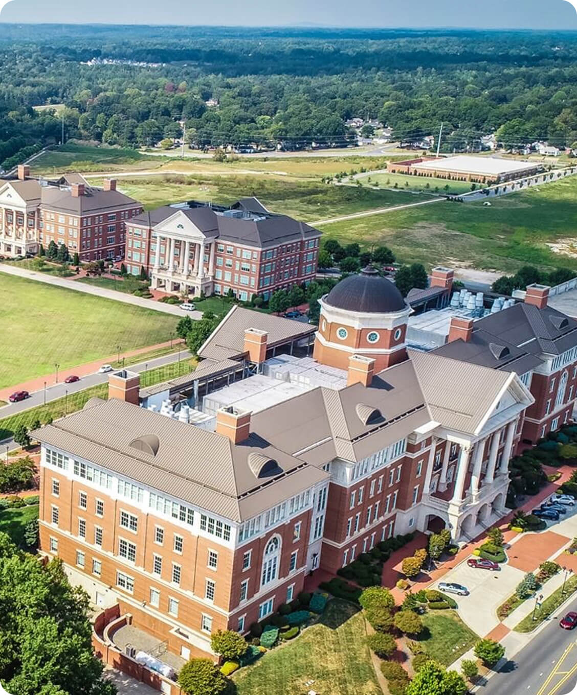 Aerial view of the WISEcode Labs campus building with a dome, surrounded by greenery and smaller buildings.
