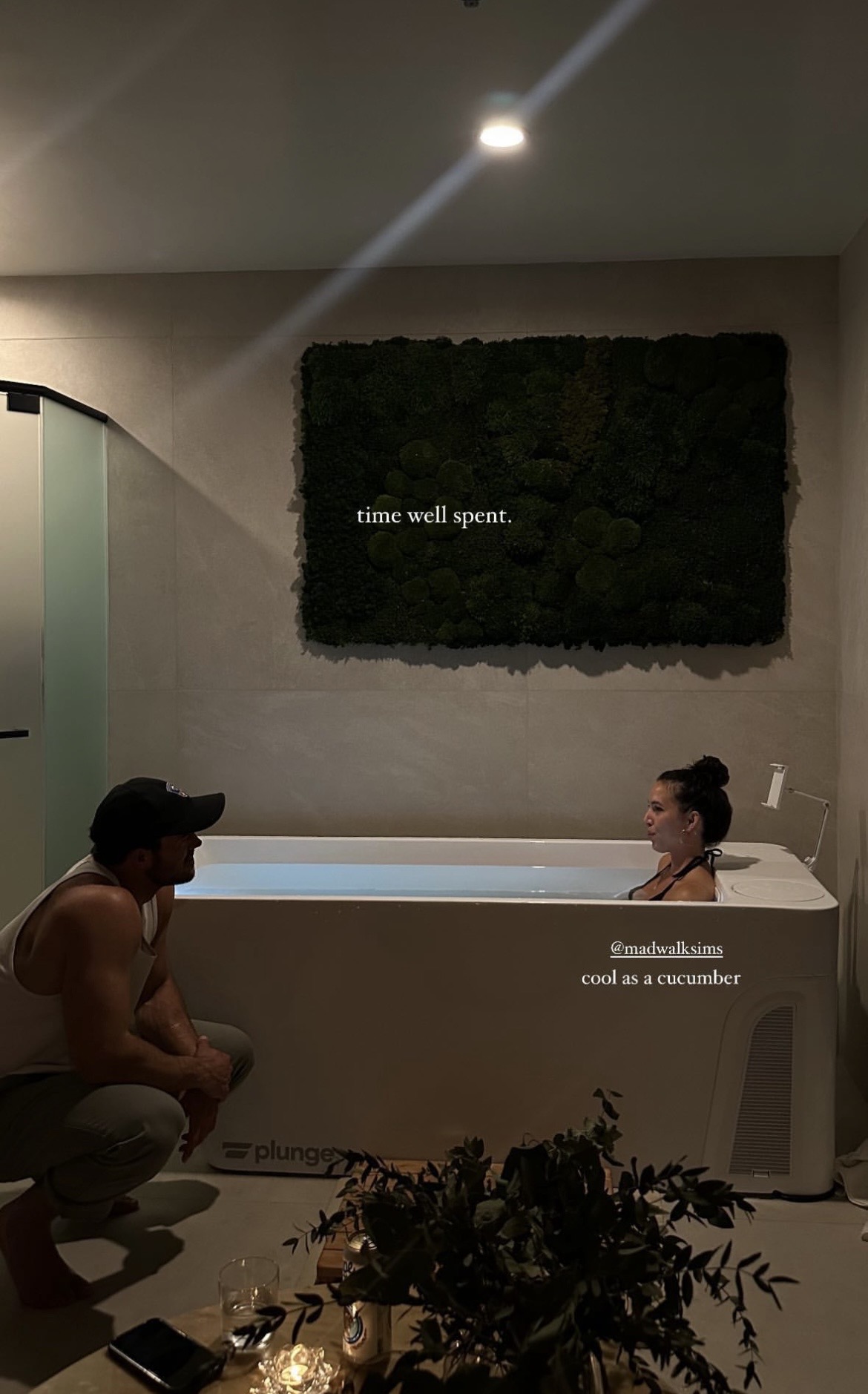 two members at the cold plunge in the moss wellness room, beside the living moss wall