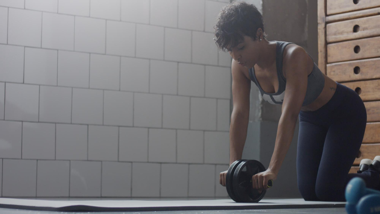 Young fit and tone up mixed race woman doing a strength training workout with an abs wheel.
