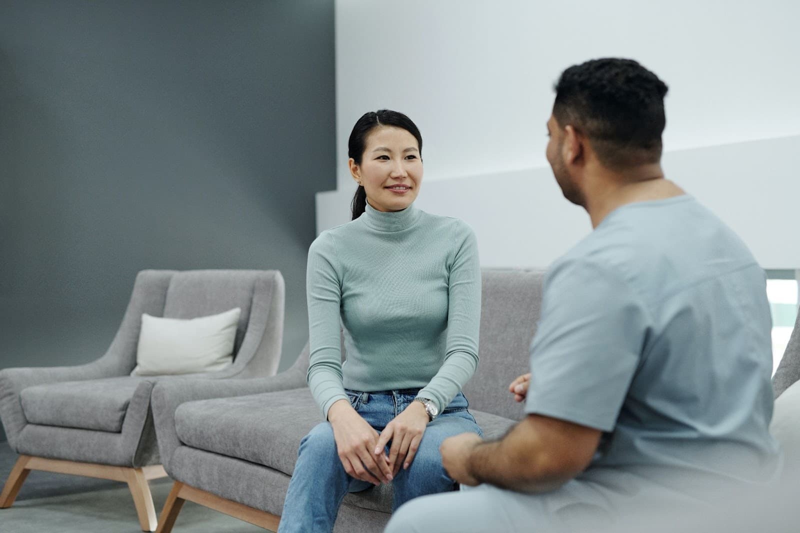 Woman and man having a conversation seated on gray couch in modern office space