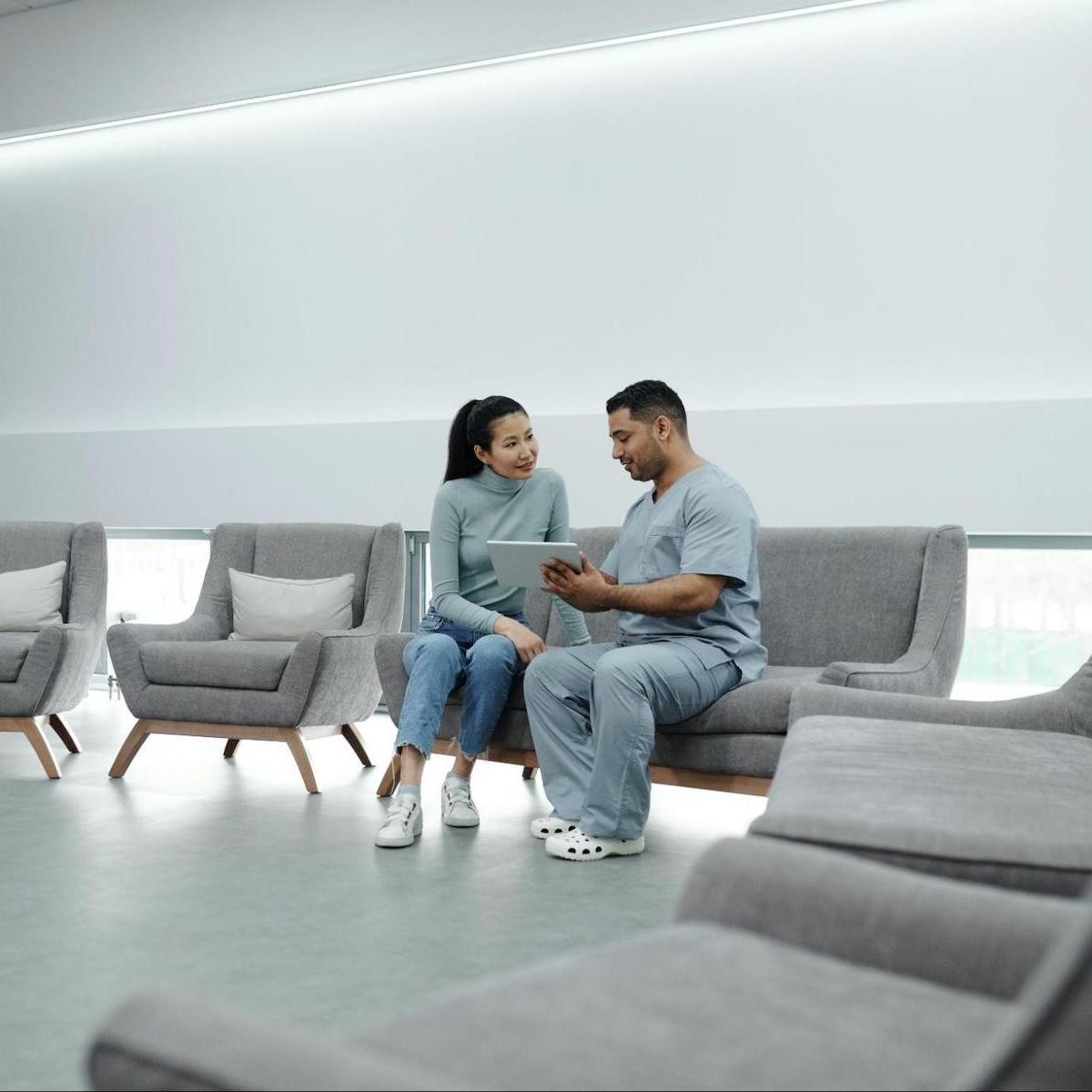 Couple reviewing tablet together while sitting on gray chairs in modern minimalist interior space