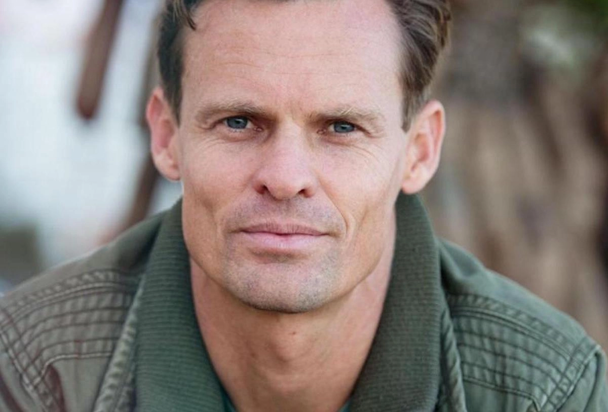 Serious-looking man in green shirt with blurred background outdoor portrait