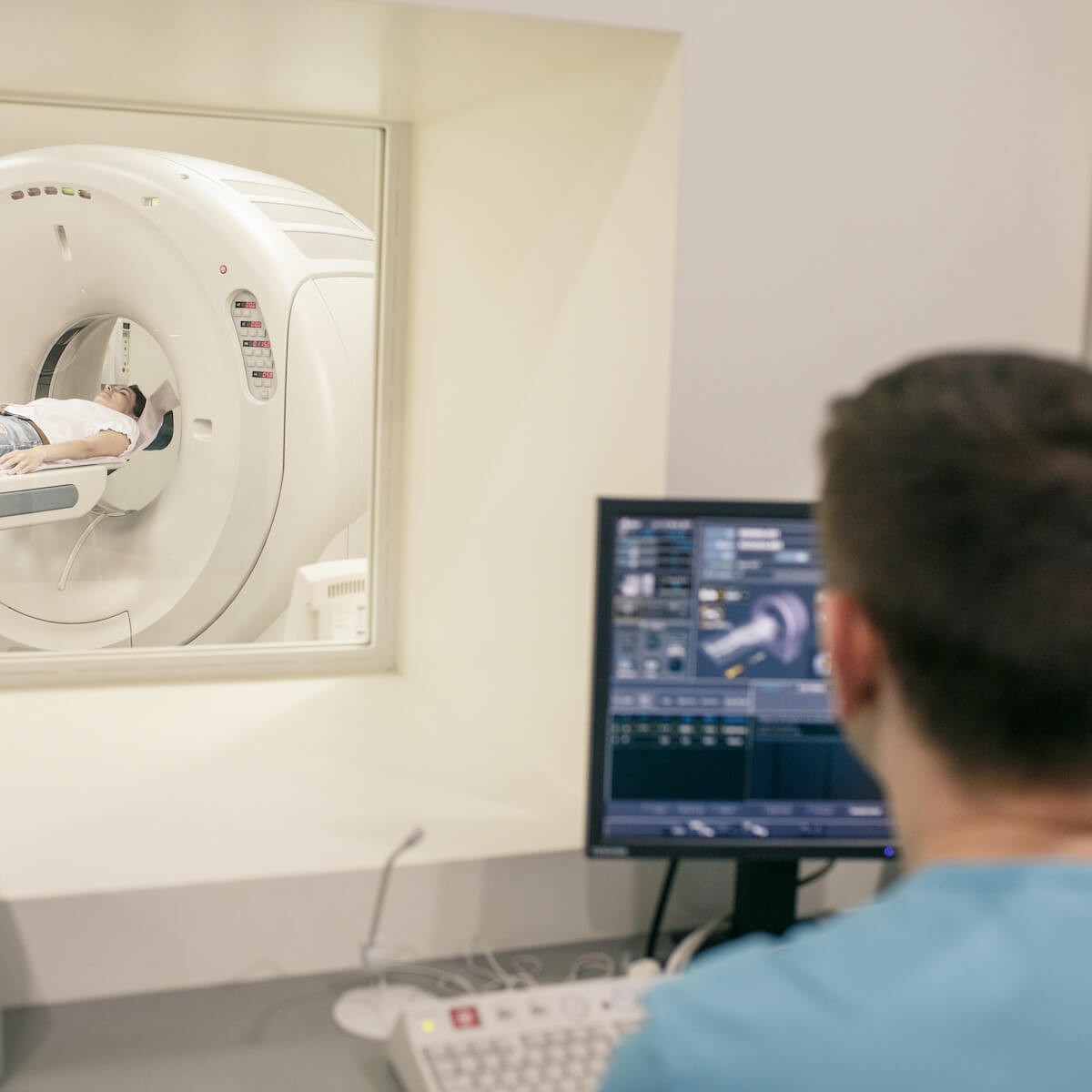 Medical technician viewing CT scan images on computer monitor in imaging facility