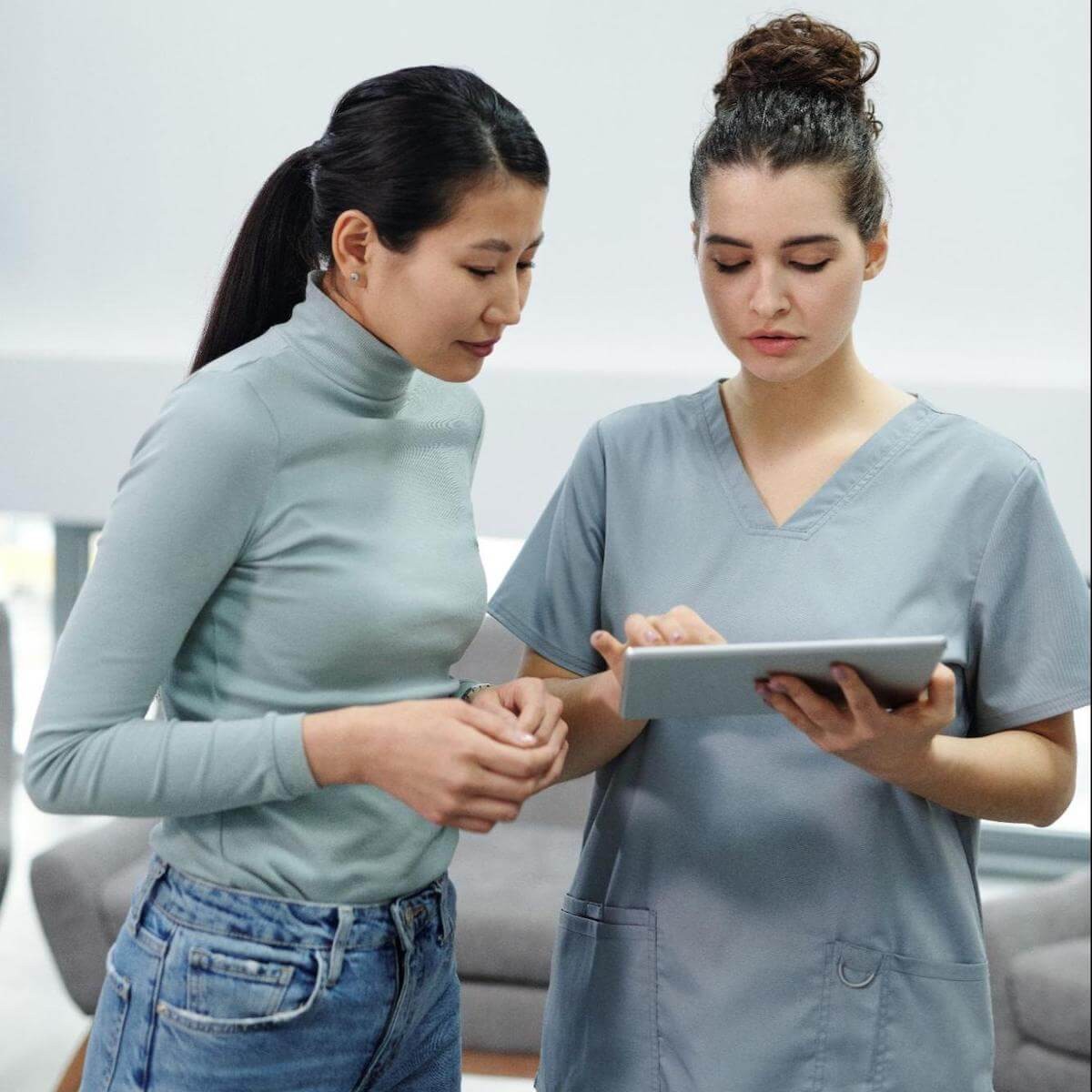 Two women reviewing information on a tablet in a medical office setting