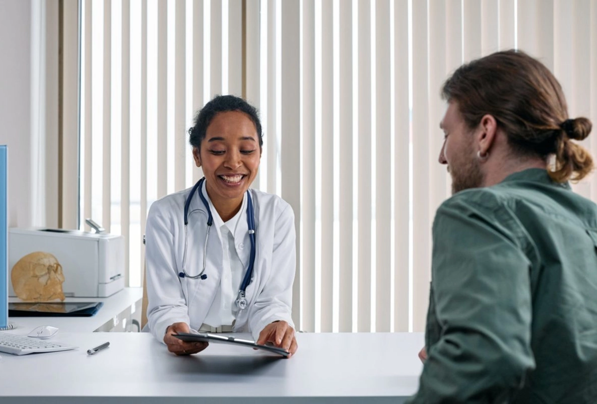 Female doctor smiling while reviewing tablet with male patient during office consultation