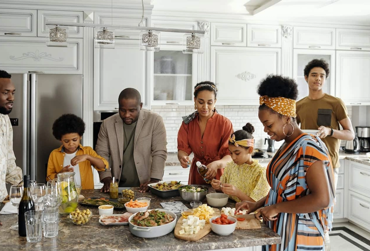 Multi-generational family preparing food together in contemporary white kitchen