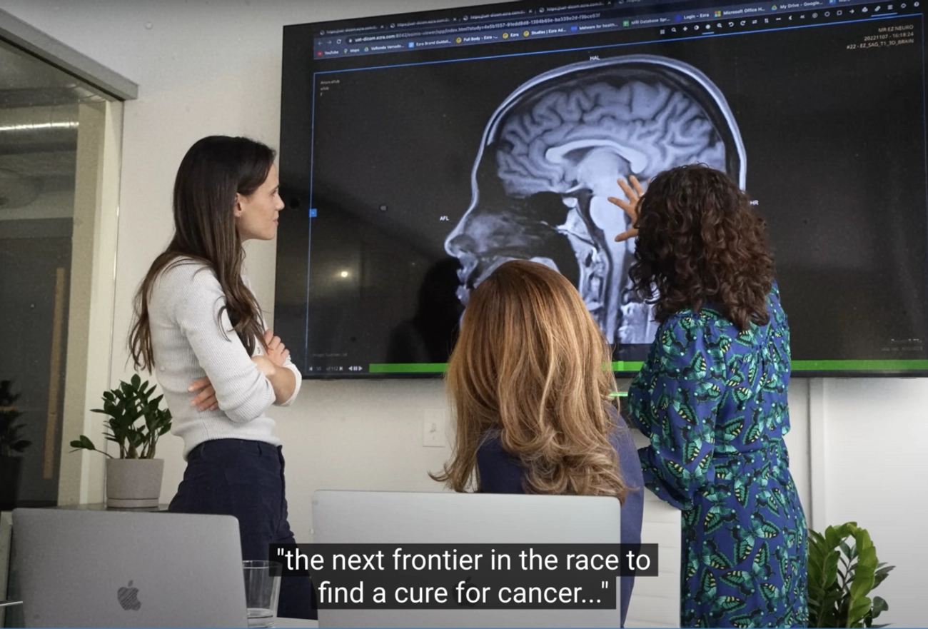 Three medical professionals examining brain MRI scan on display screen in research setting