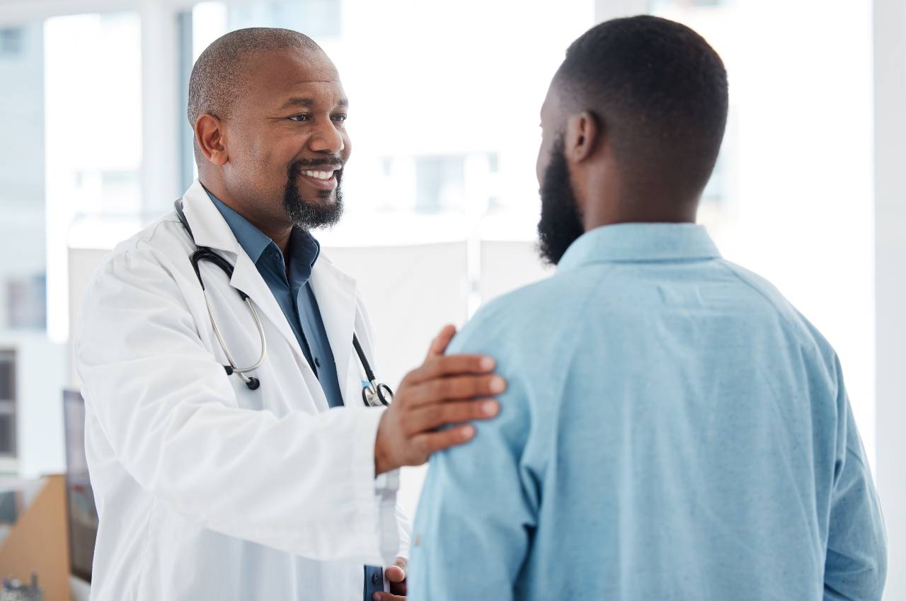 Doctor in white coat speaking with patient in modern medical office with city skyline view