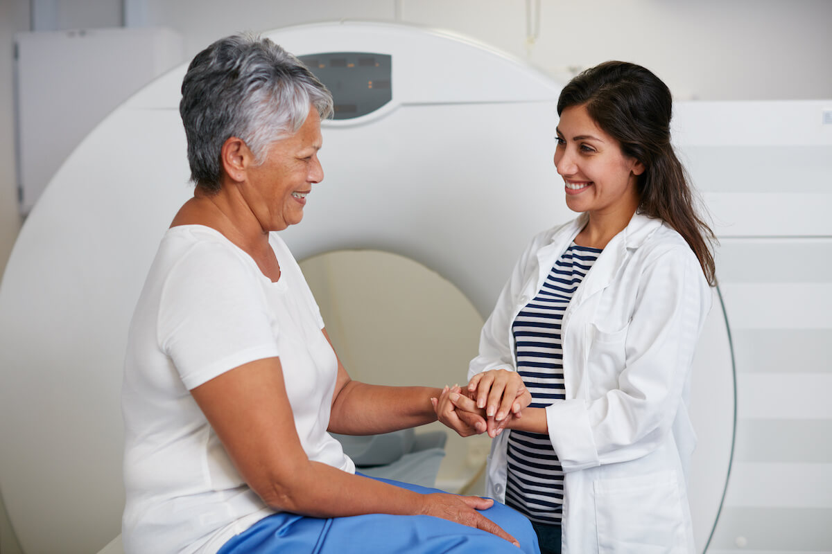 Female doctor consulting with smiling senior patient in medical imaging facility