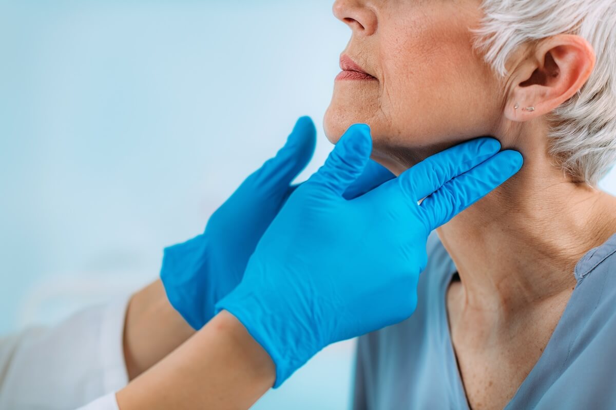 Thyroid cancer symptoms: doctor checking a senior woman