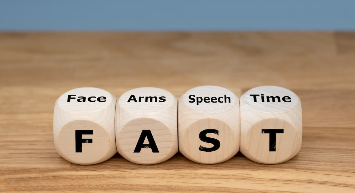 Wooden dice displaying FAST stroke recognition acronym: Face, Arms, Speech, Time