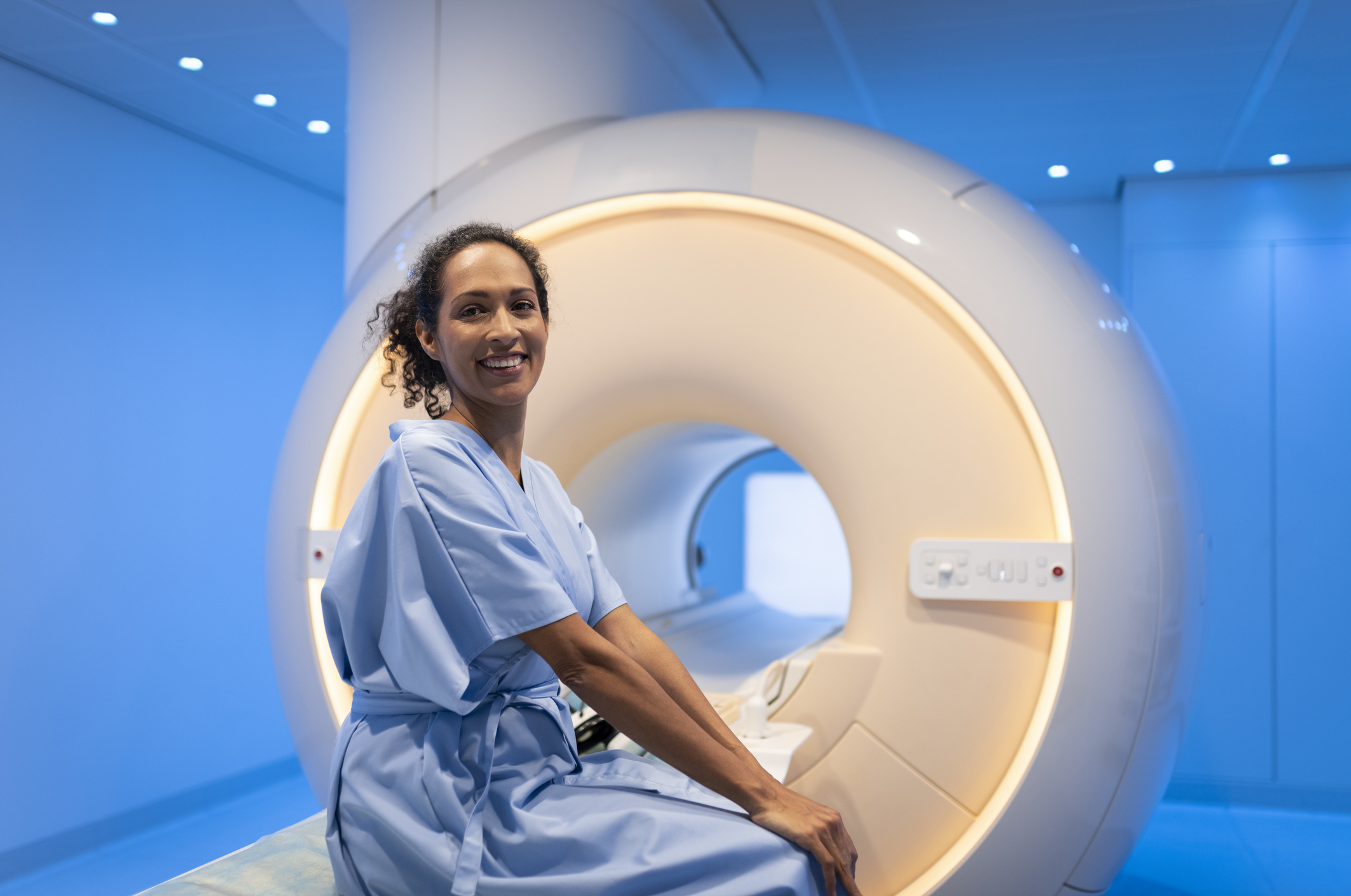 Female patient sitting on bed before MRI scan.