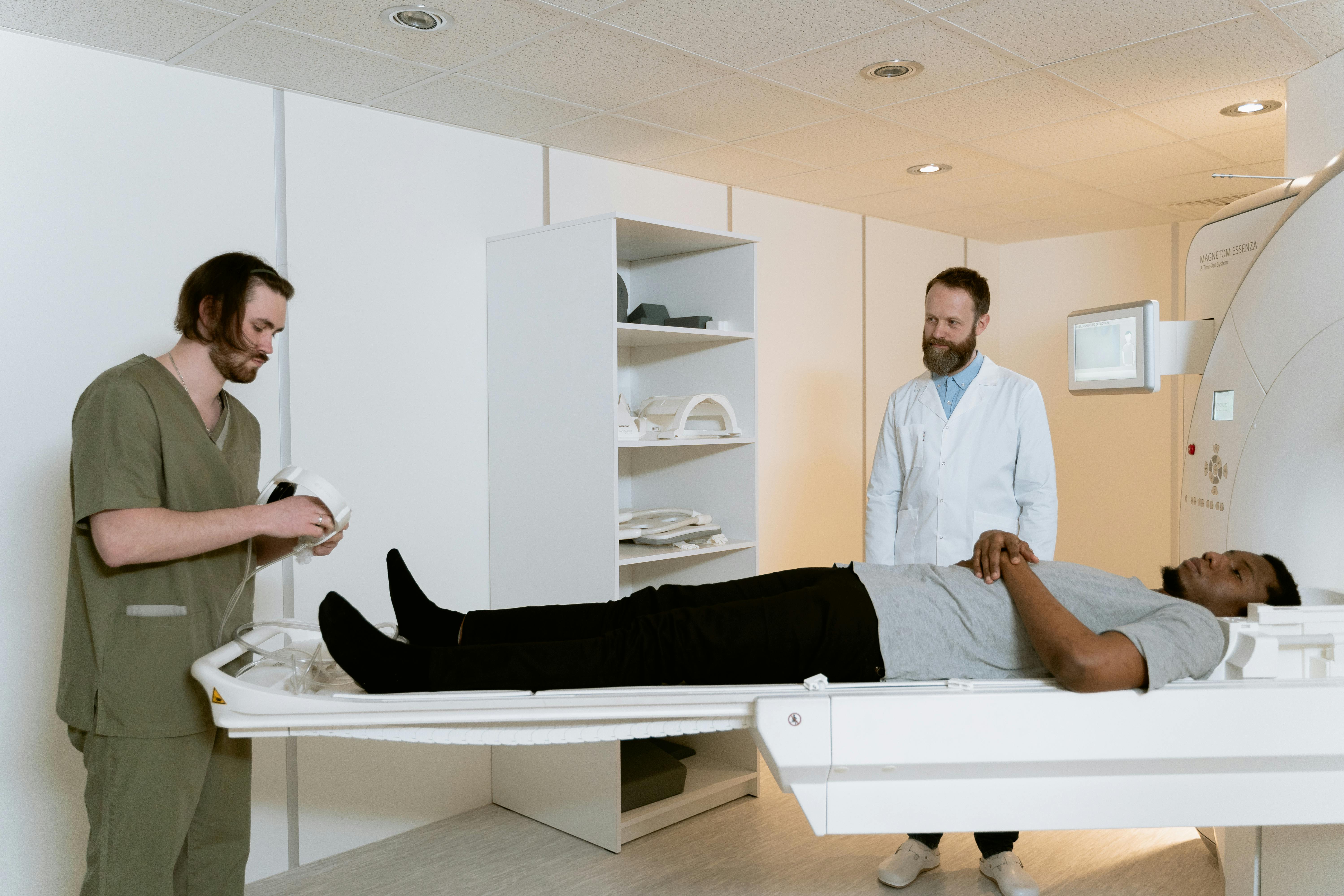 Man laying in an MRI with two medical practitioners.