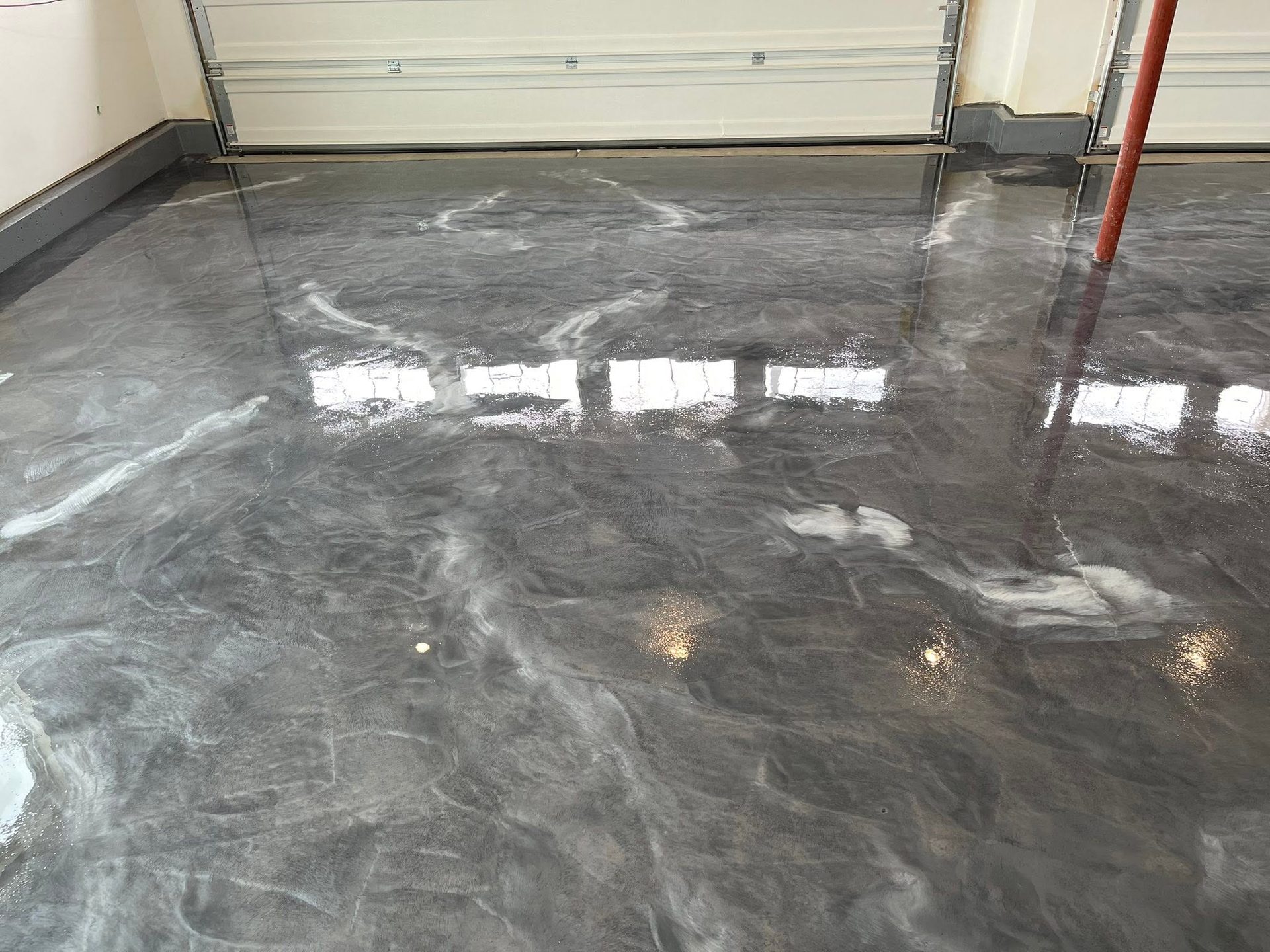 Shiny silver marbled metallic epoxy flooring in a garage with a closed door in the background.