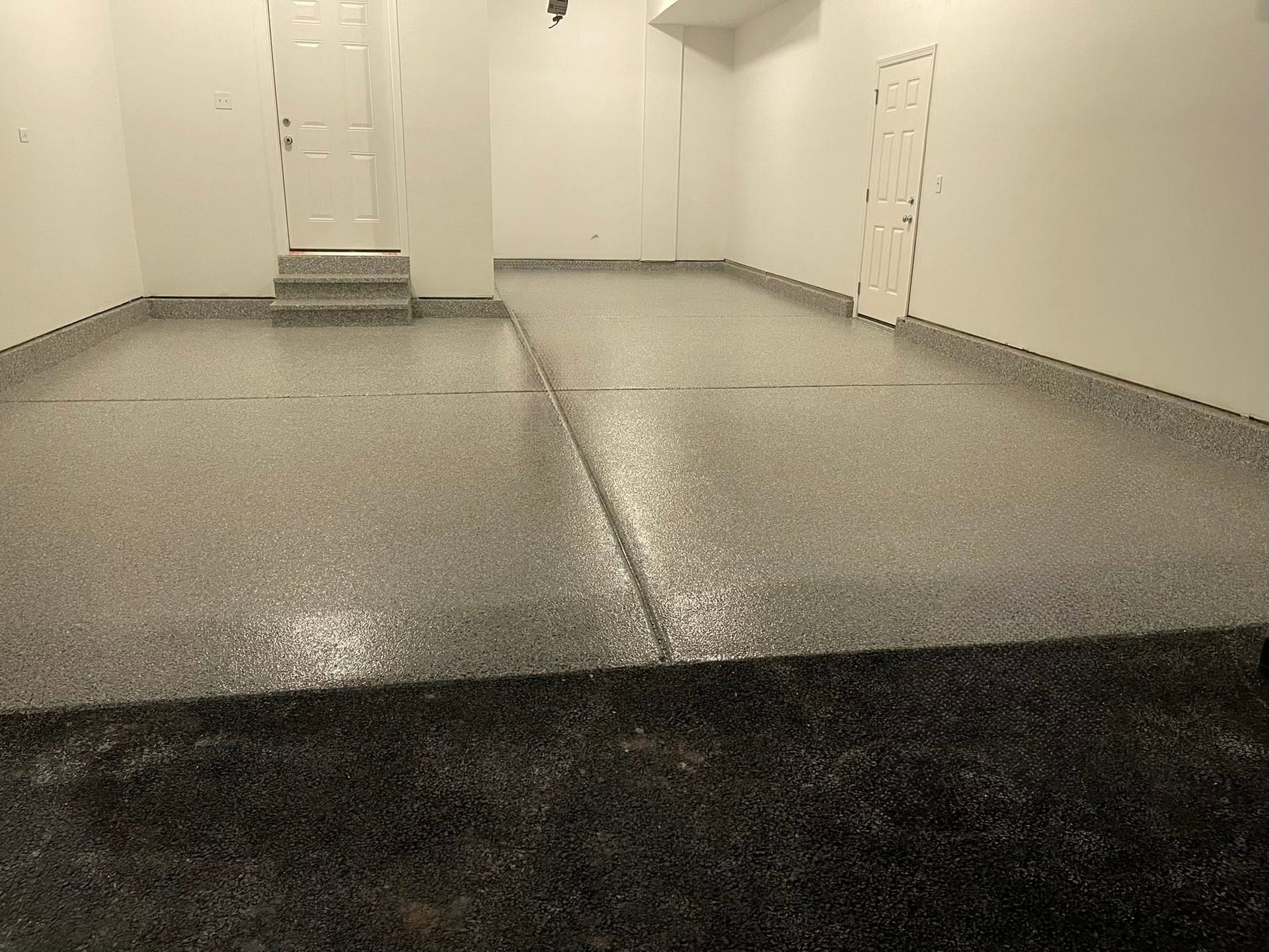 Clean, empty garage interior with smooth gray epoxy floor and white walls.
