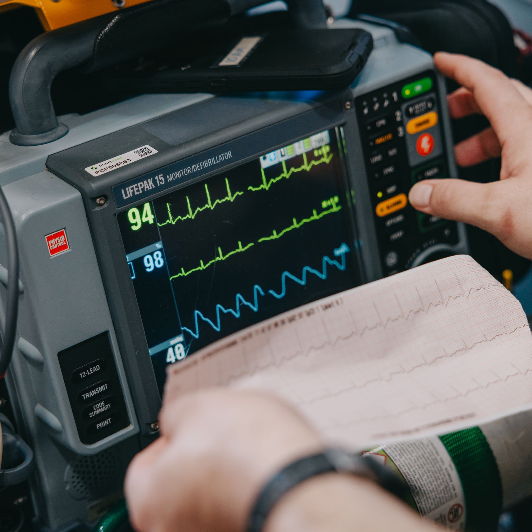 Paramedic reading vital signs on a cardiac monitor during transport