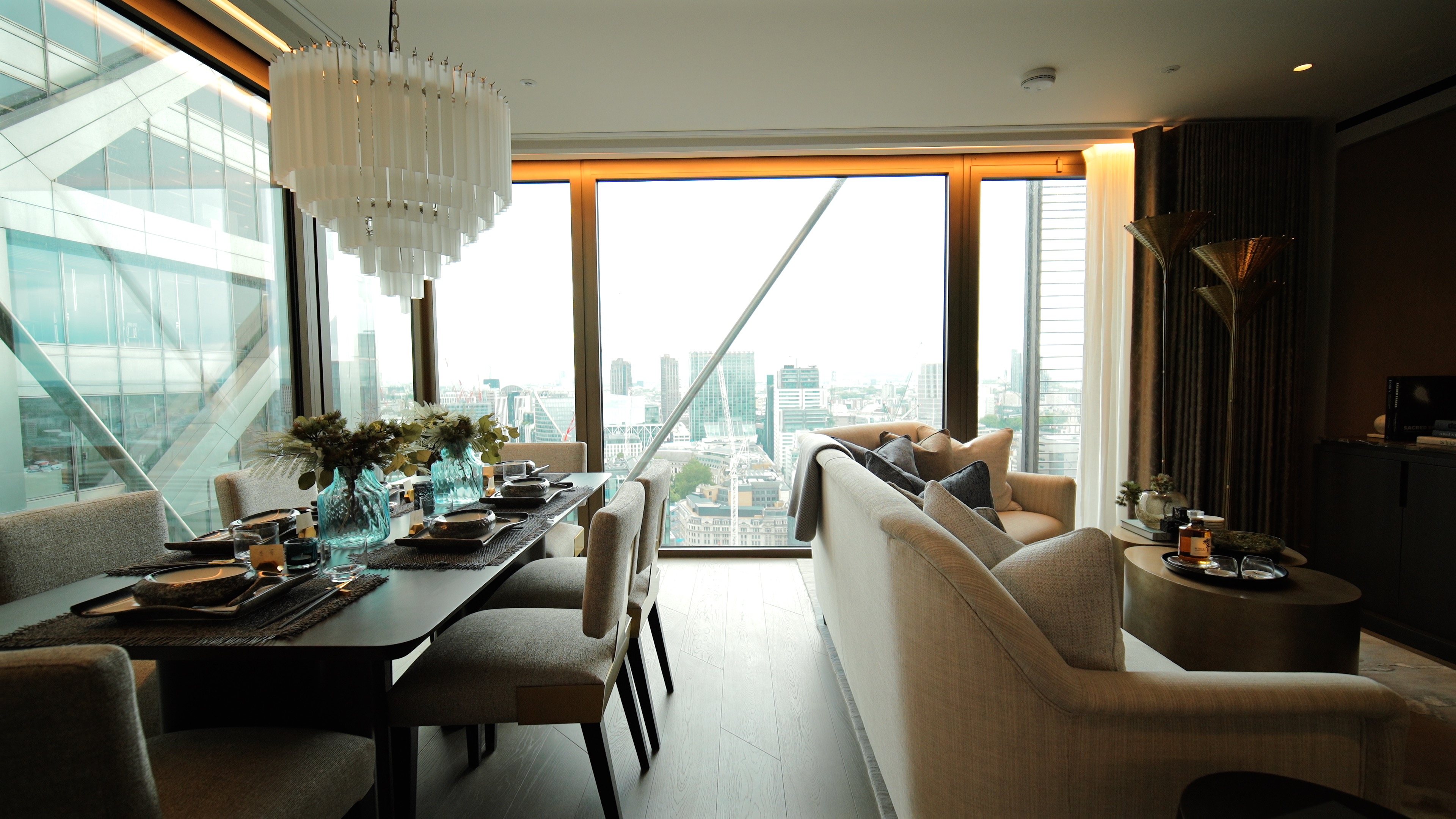 Modern dining and living area with large window offering a cityscape view, neutral furnishings, and decor.