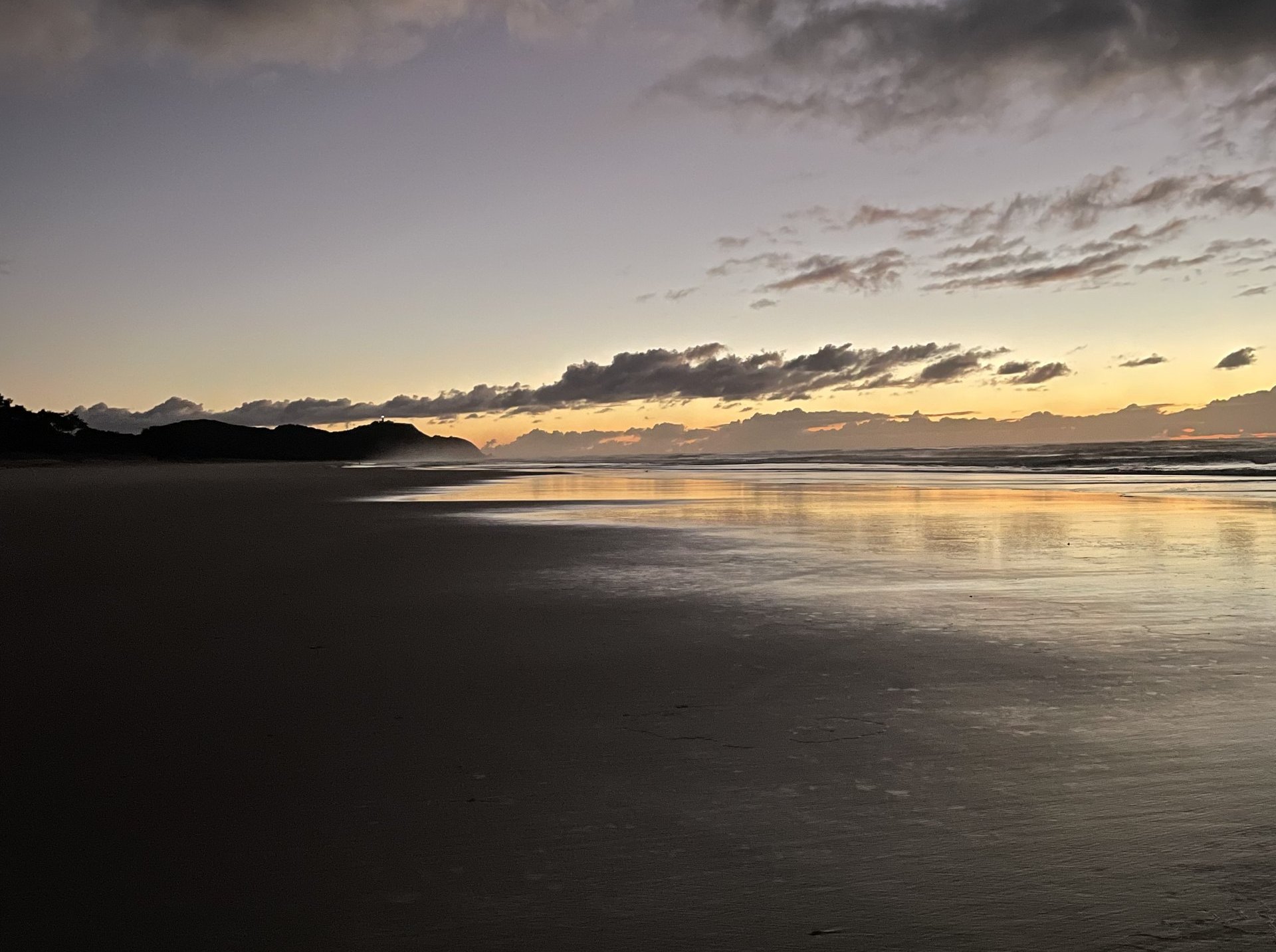 A wide, dim beach at dusk under a heavy sky
