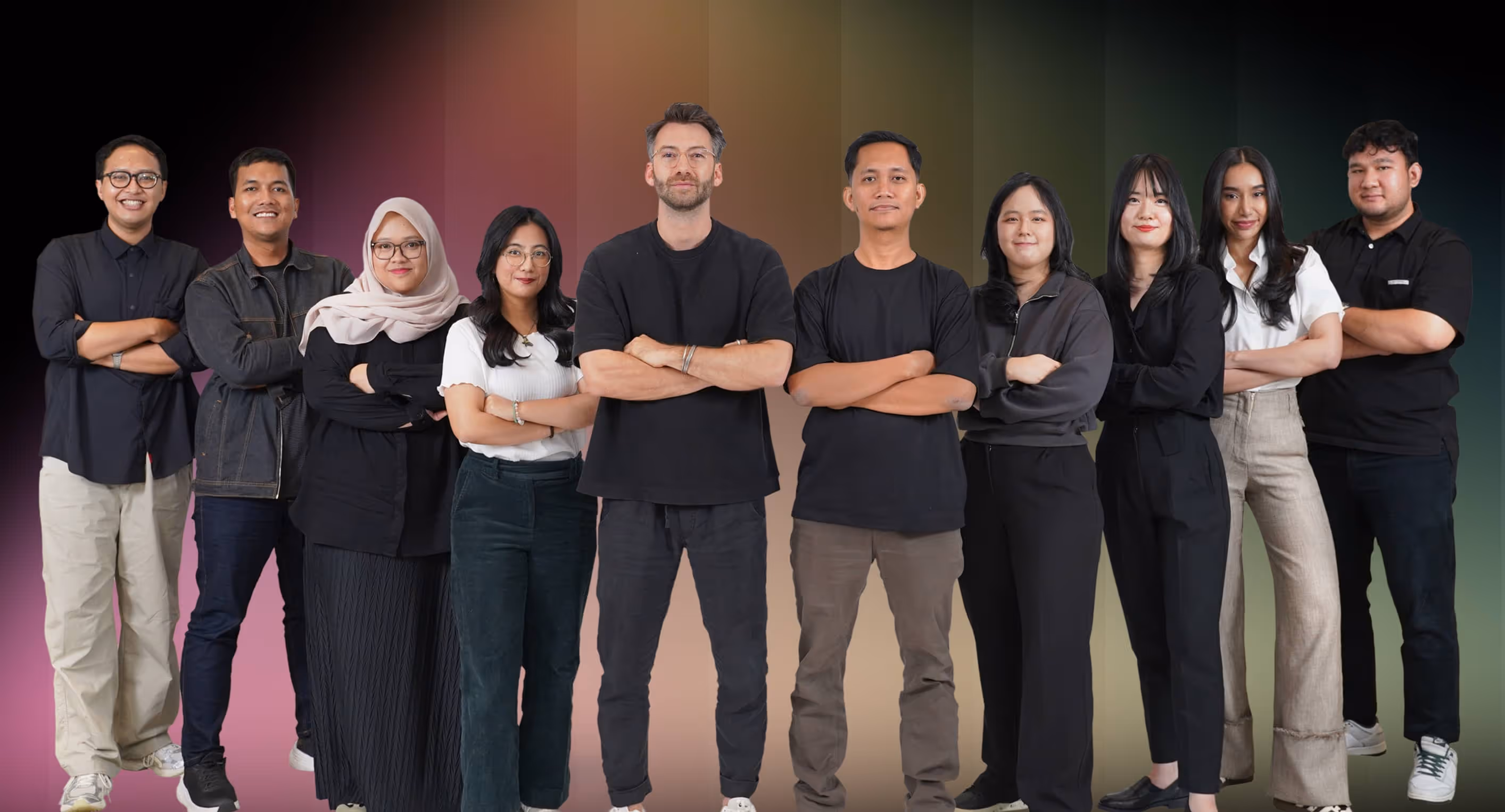 Group of ten diverse young adults standing side by side with arms crossed in front of a gradient background.