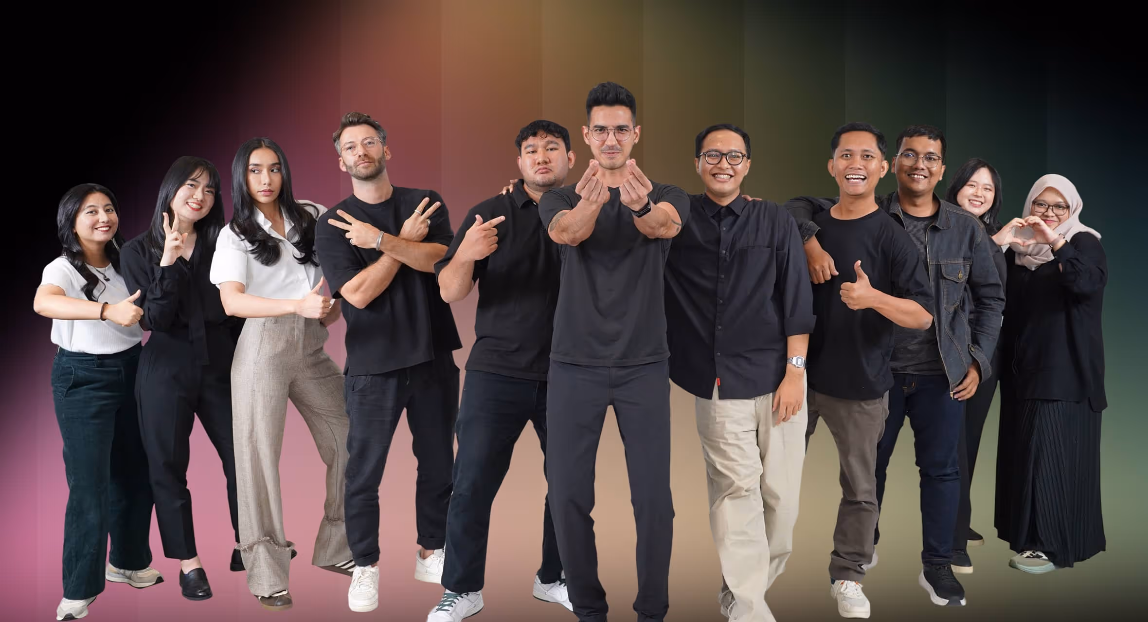 Group of eleven diverse young adults standing in a line, smiling and making various hand gestures.