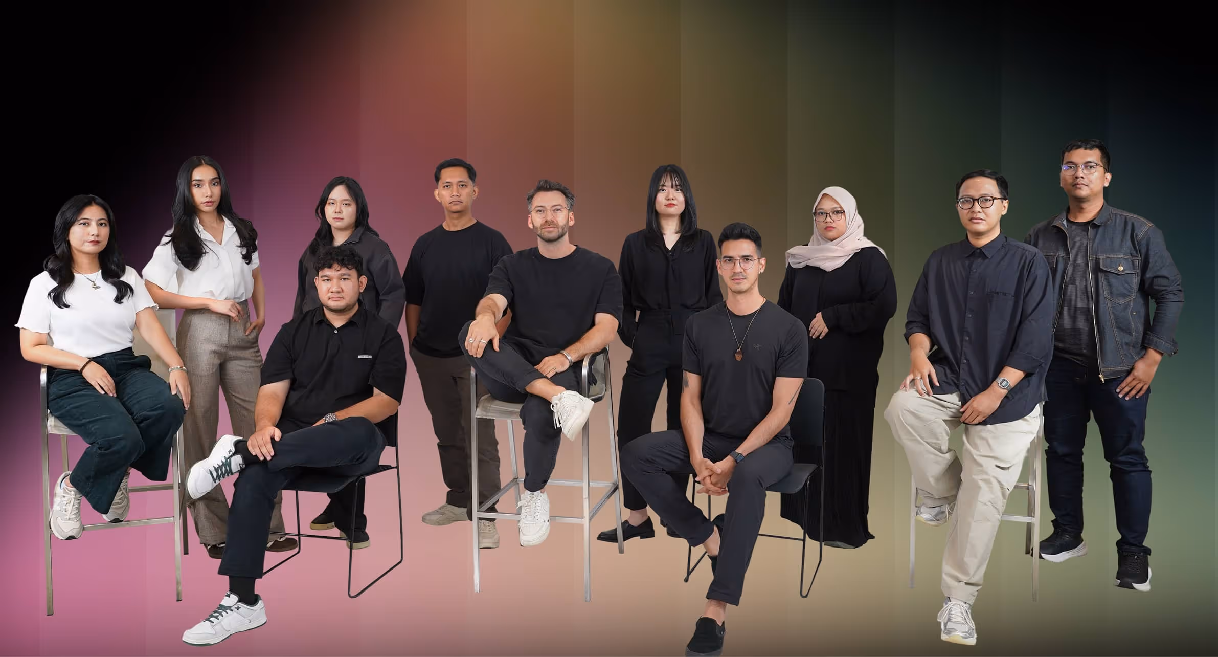 Group of eleven diverse individuals posing against a gradient background, some sitting on chairs or stools and others standing.