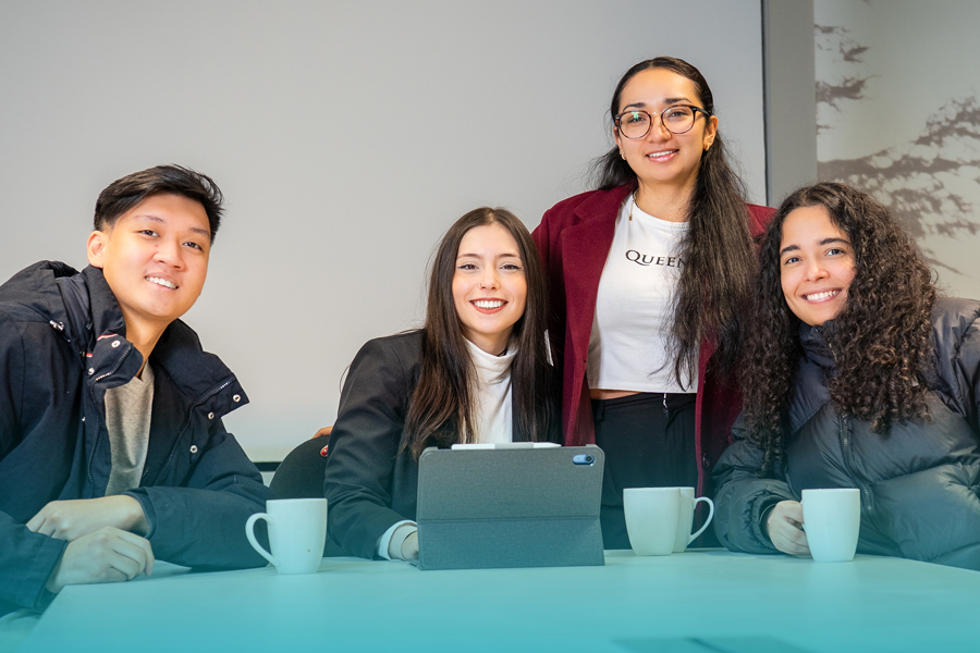 Four Danford College students smiling together at a table with laptops and coffee