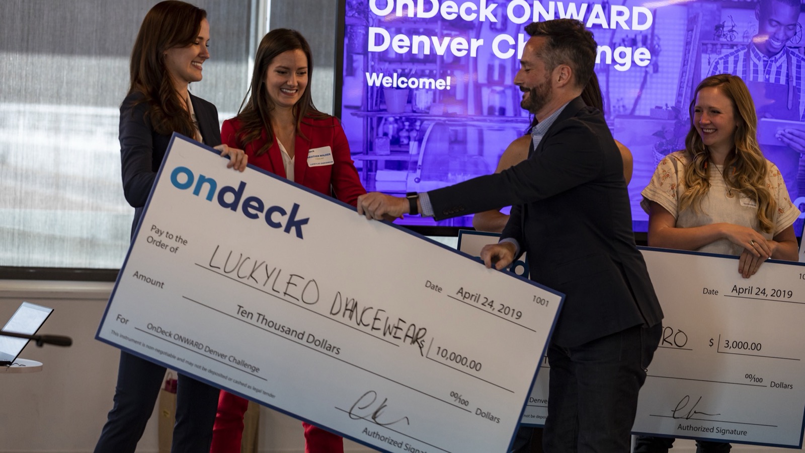 OnDeck ONWARD Denver Challenge winners holding a large-format $10,000 check made out to Luckyleo Dancewear, April 2019.