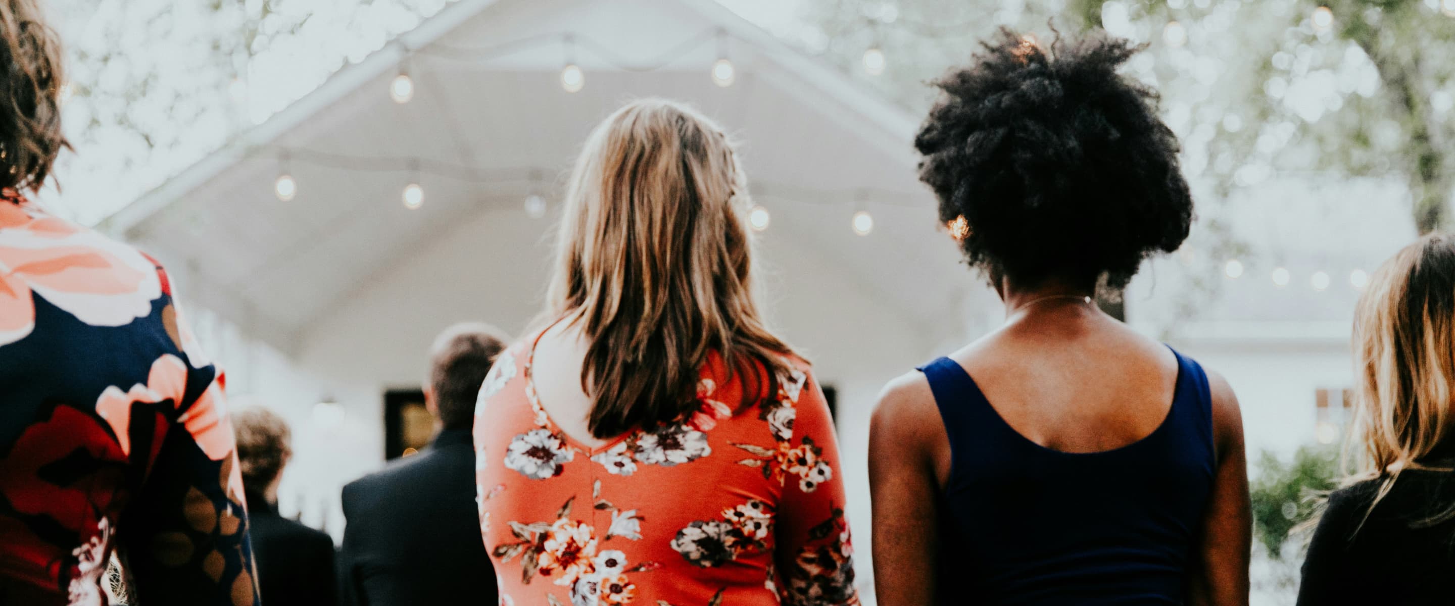 Two women standing outdoors at a community gathering.