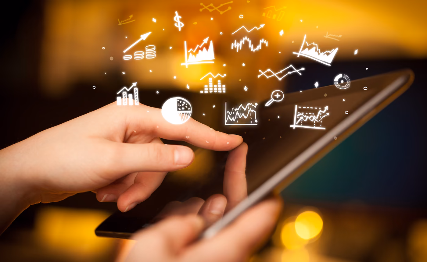 two hands use a tablet below floating marketing charts and graphs