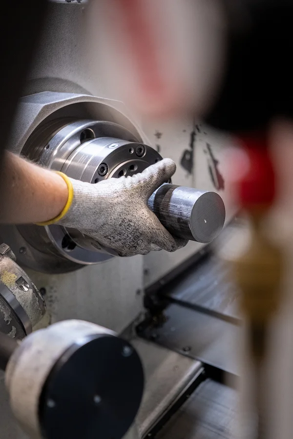 Worker clamping a metal blank in a CNC lathe