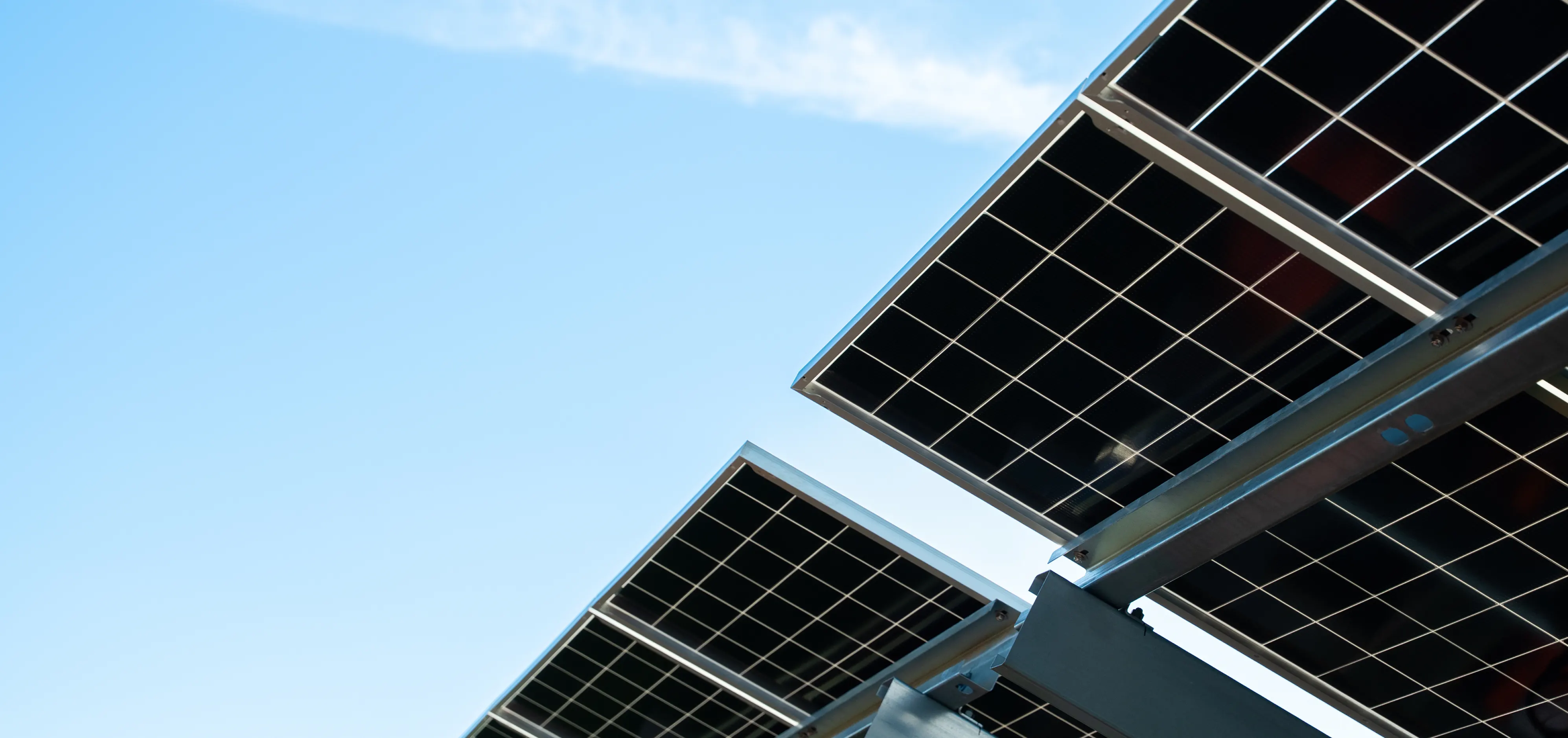 Panneaux photovoltaïques sur structures métalliques, vus en contre-plongée sur fond de ciel bleu