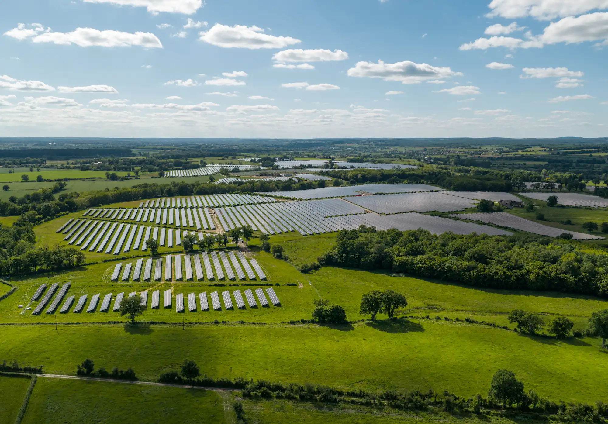 Vue aérienne d'une centrale solaire au sol dans un paysage verdoyant