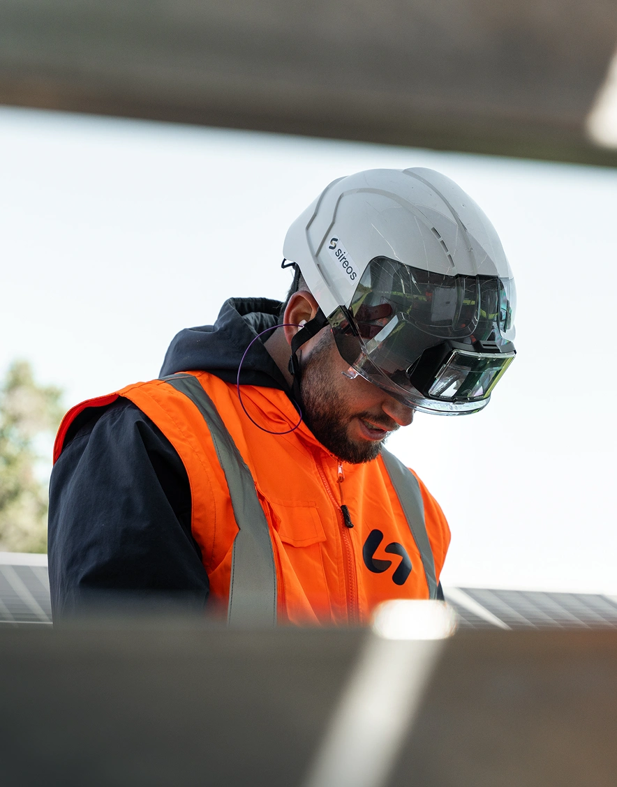 Technicien Sireos casqué inspectant un panneau solaire