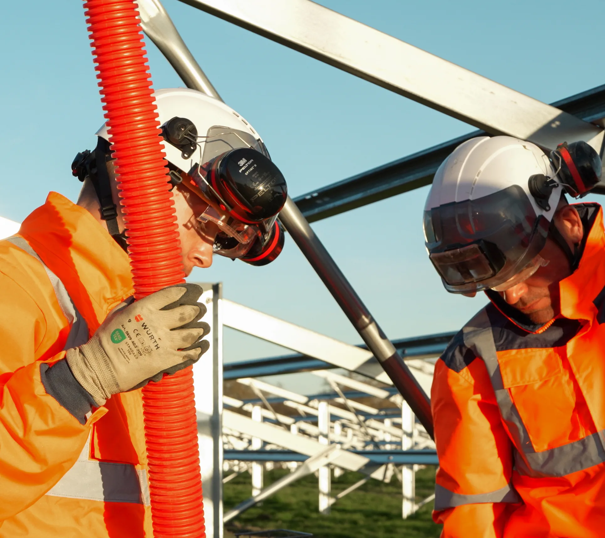 Deux techniciens Sireos installant une gaine électrique sous une structure photovoltaïque