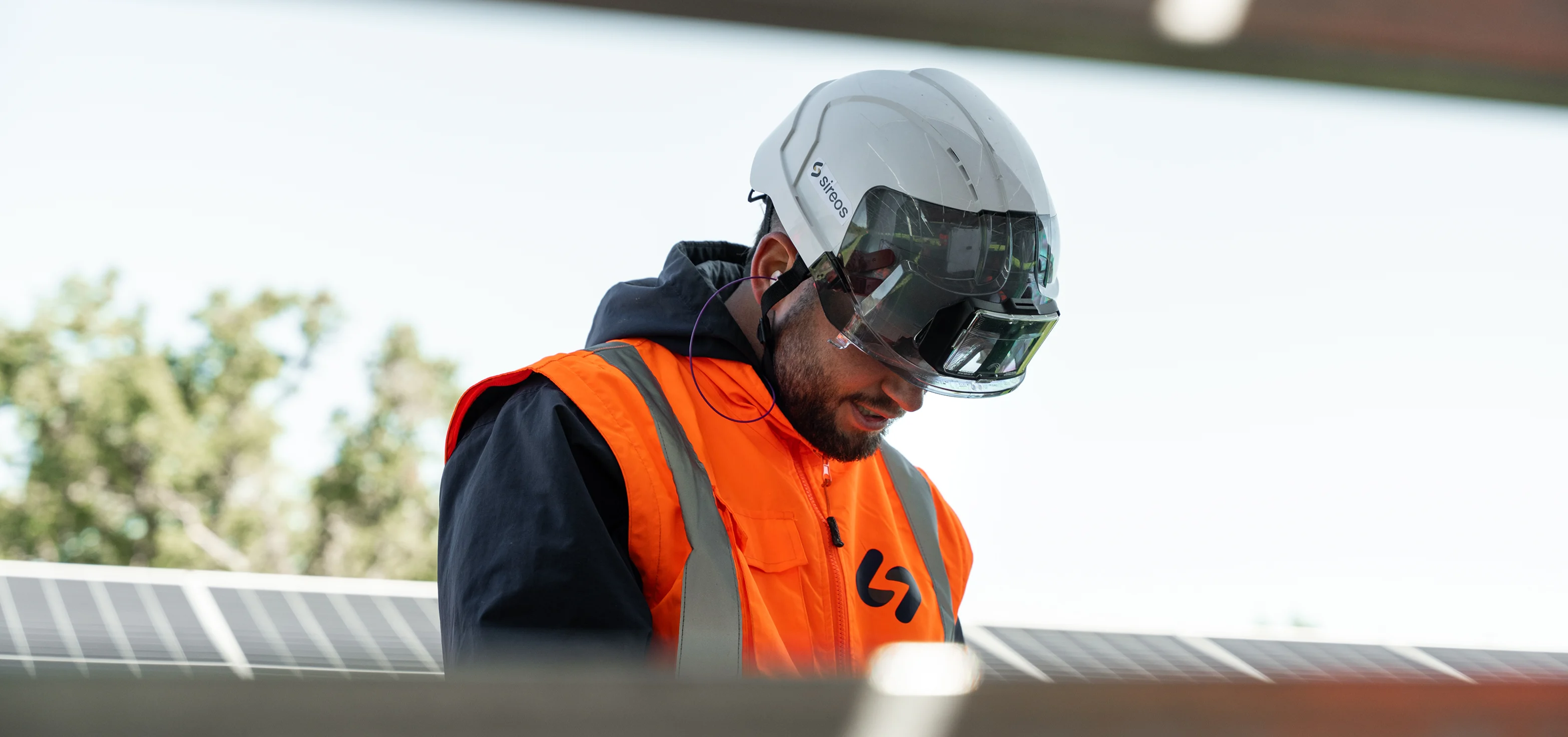 Technicien Sireos casqué inspectant un panneau solaire
