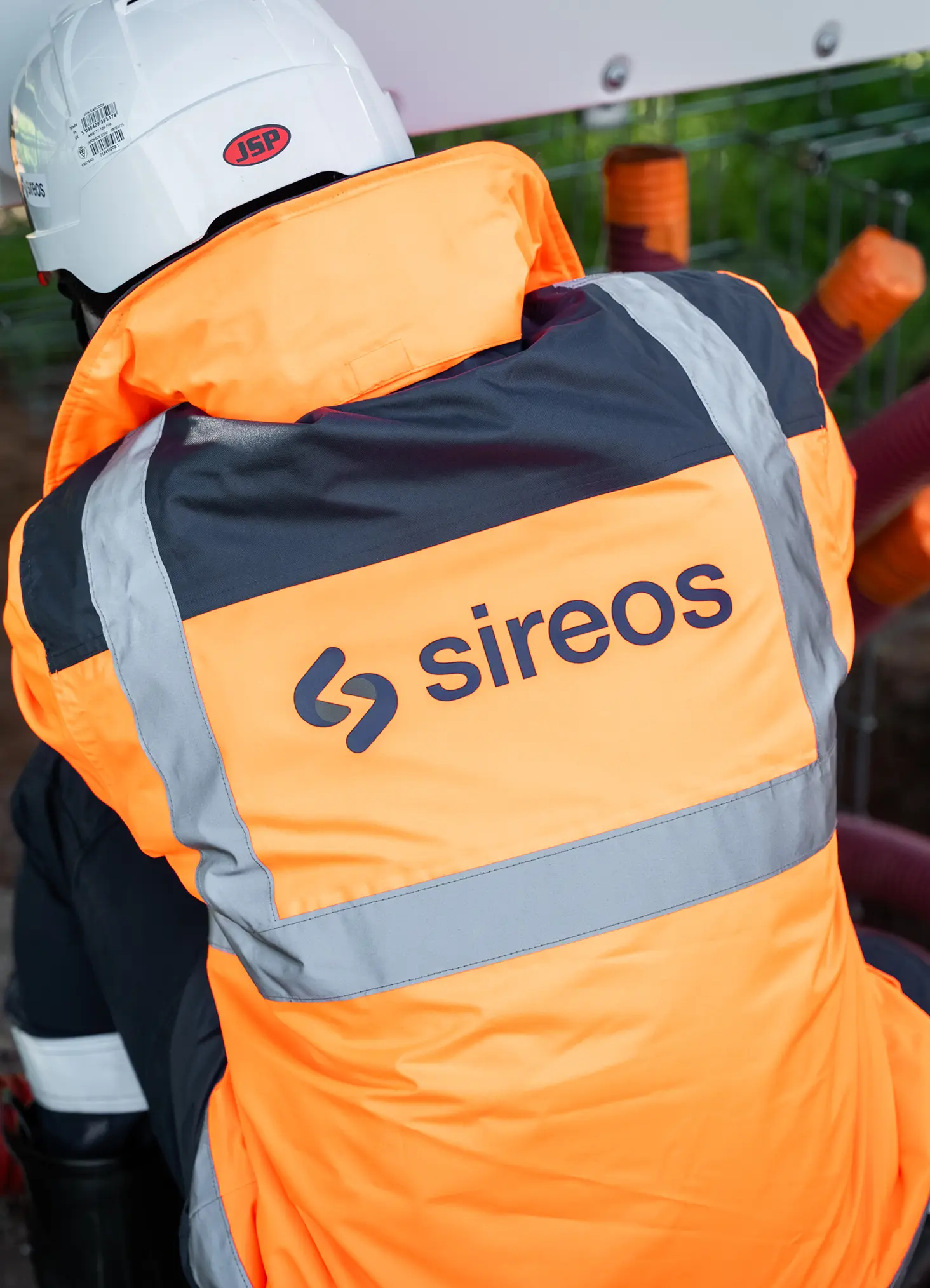 Technicien Sireos de dos, veste orange au logo Sireos