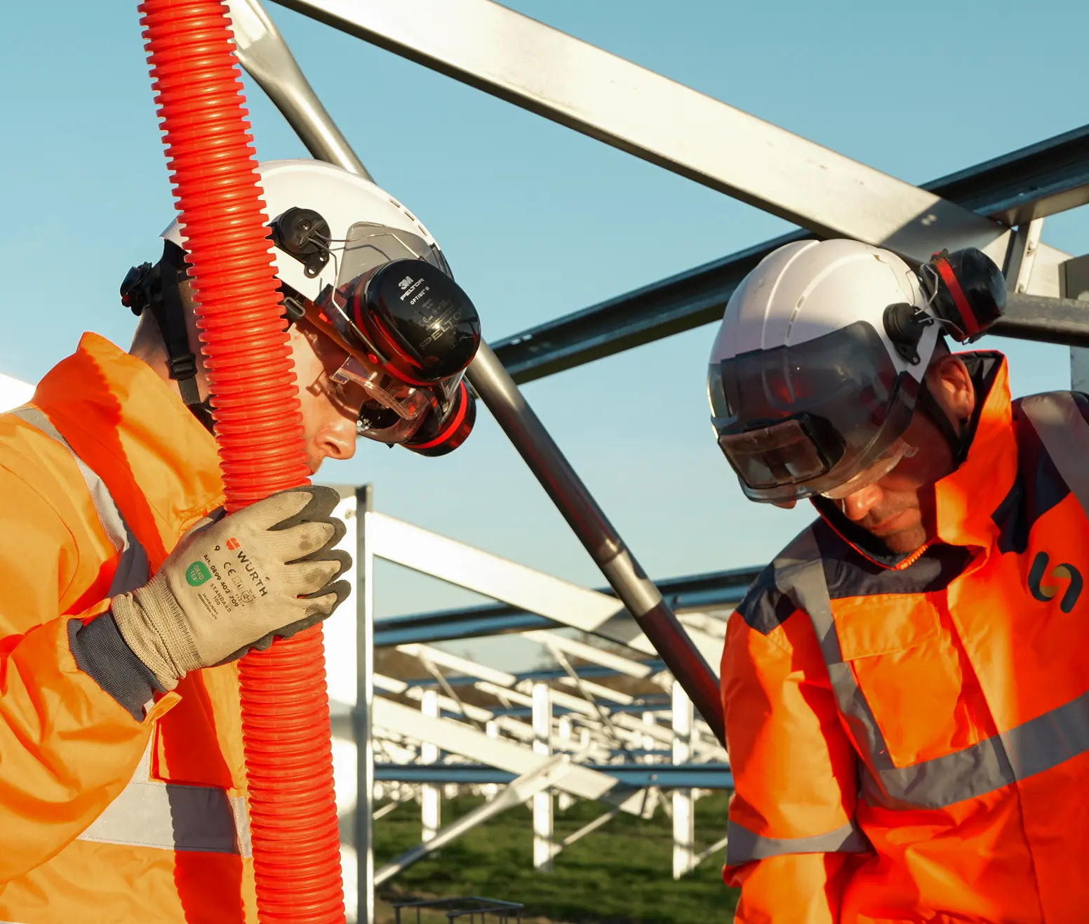 Deux techniciens Sireos casqués manipulant une gaine électrique
