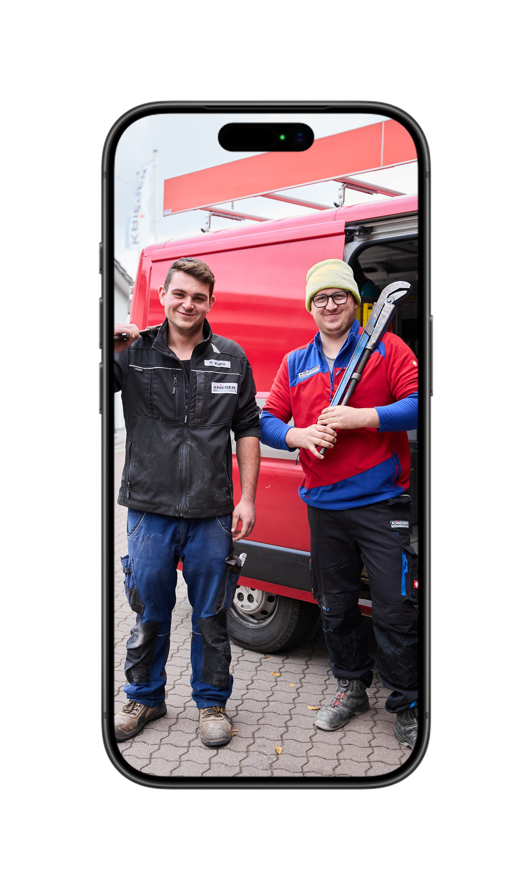 Zwei lächelnde Mitarbeiter stehen vor rotem Hintergrund; der Mann hält eine Rohrzange in der Hand.
