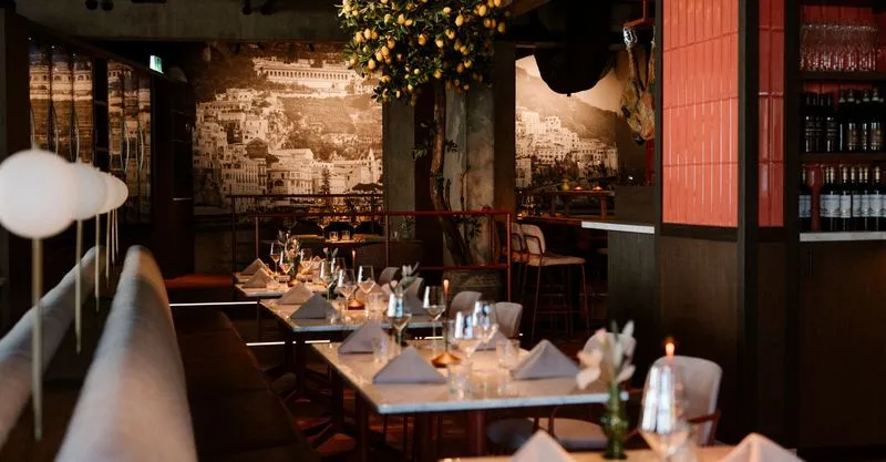 Gedekte tafels met witte servetten en een citroenboom in het vernieuwde Alberto's Italian in Nijkerk